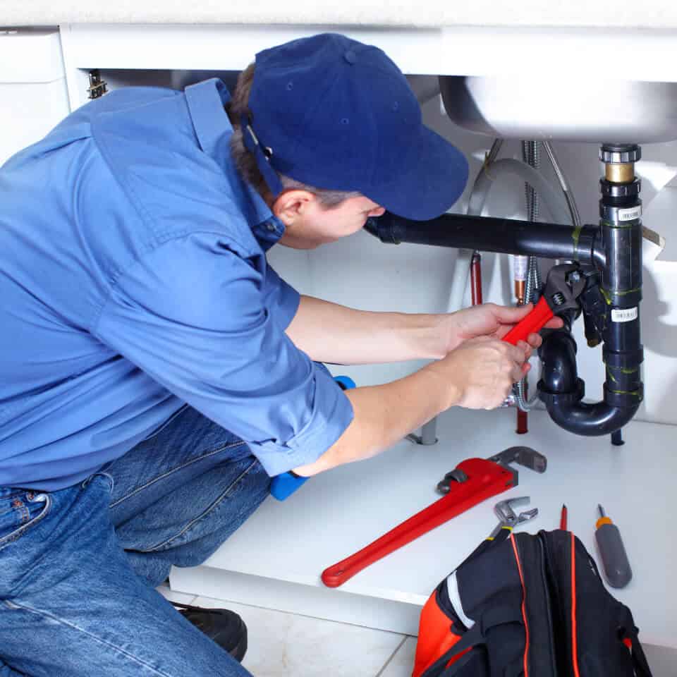 Plumber fixing pipes in a residence.