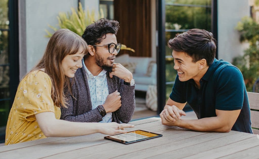 a group of people sitting at a table looking at a tablet